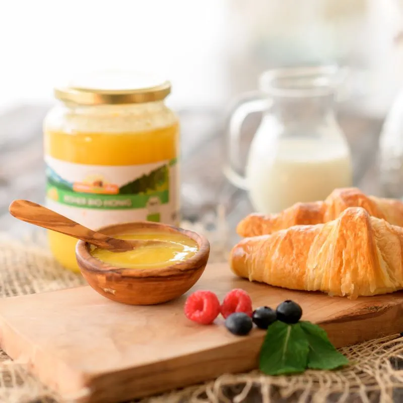 Honigglas mit Honig, Croissant und frischen Früchten